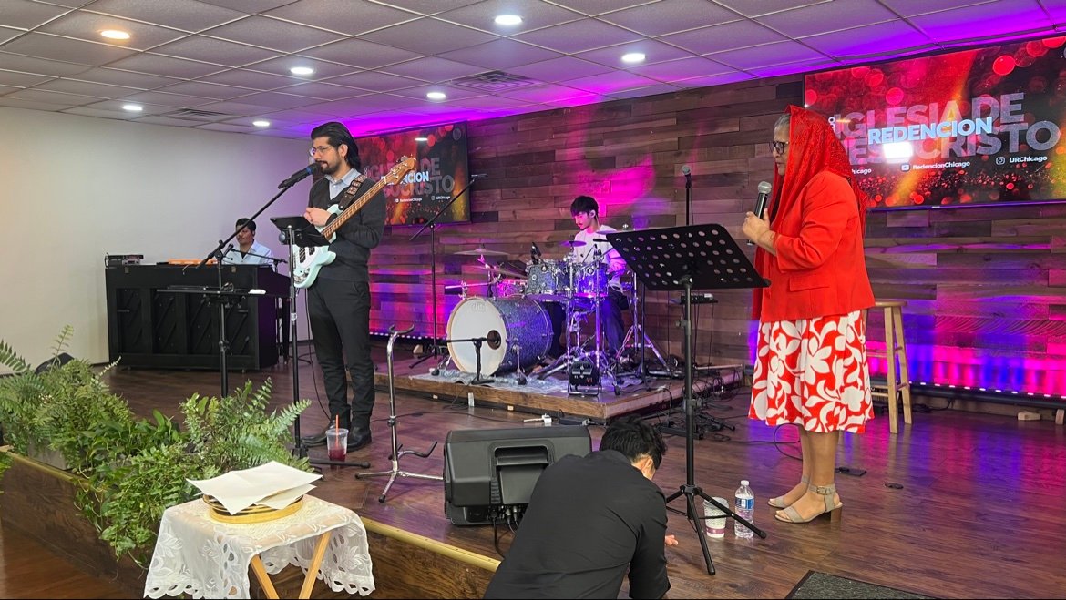 El grupo de alabanza en la plataforma mientras una hermana canta con micrófono